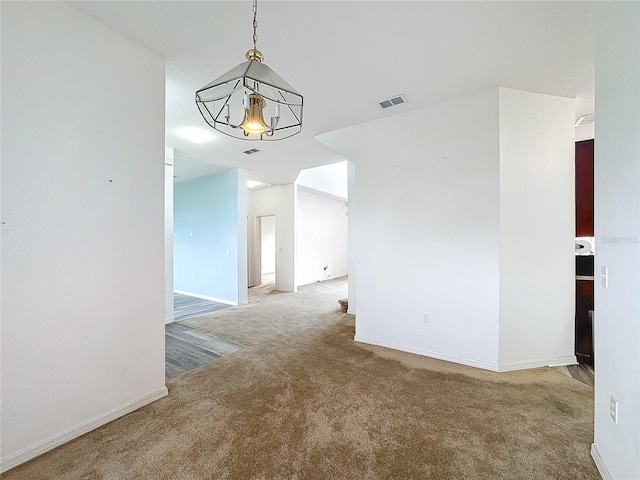 spare room with carpet and a notable chandelier