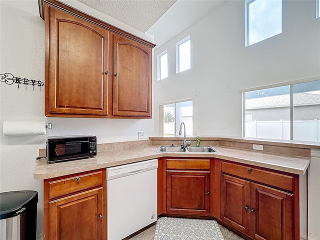 kitchen featuring dishwasher, a towering ceiling, a textured ceiling, and sink