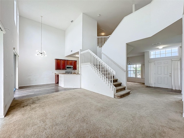 unfurnished living room featuring a high ceiling, an inviting chandelier, and wood-type flooring