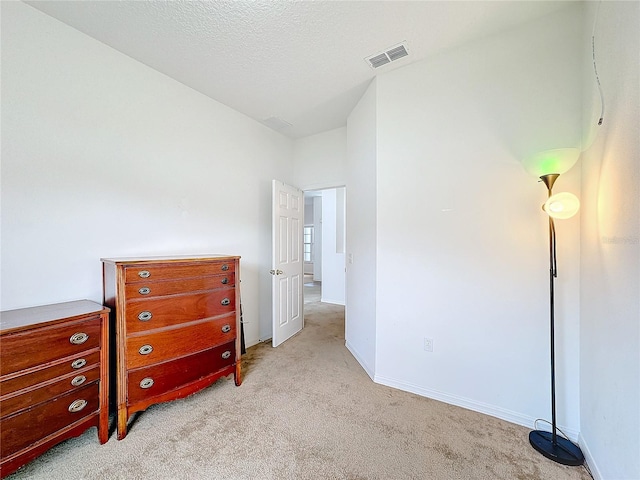 bedroom featuring light colored carpet and a textured ceiling