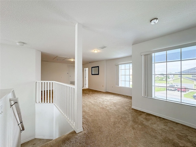 carpeted spare room featuring a textured ceiling