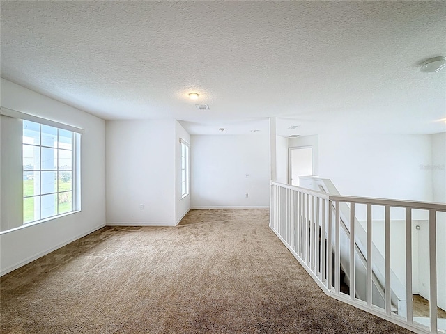 carpeted empty room with a textured ceiling