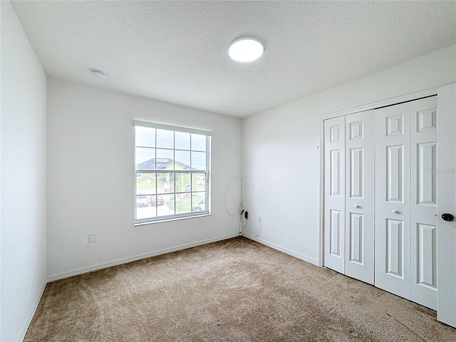 unfurnished bedroom with carpet, a textured ceiling, and a closet