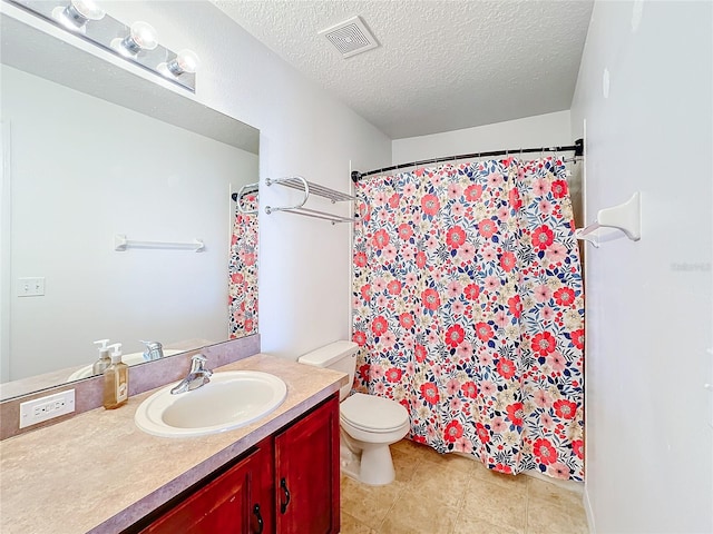 bathroom featuring toilet, vanity, a textured ceiling, and tile patterned floors