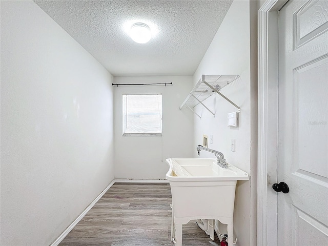 washroom featuring hookup for a washing machine, light wood-type flooring, and a textured ceiling