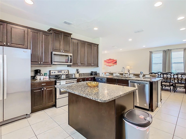 kitchen featuring a center island, stainless steel appliances, sink, kitchen peninsula, and light tile patterned floors