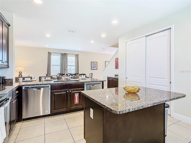 kitchen with light tile patterned flooring, a kitchen island, dark brown cabinets, and stainless steel appliances