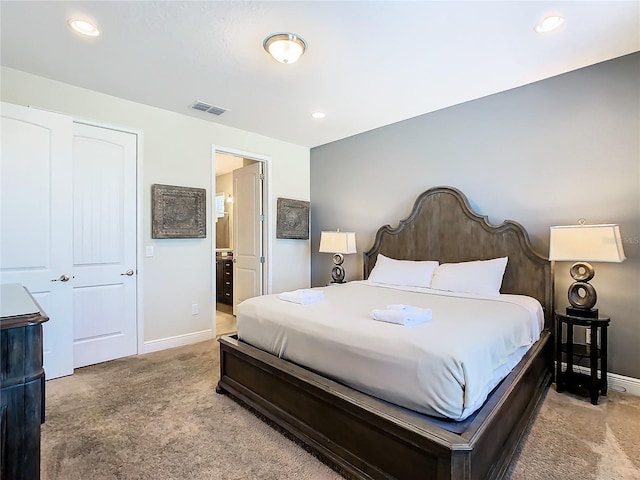 carpeted bedroom with ensuite bathroom and a closet