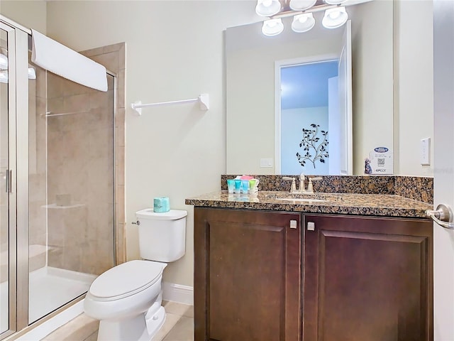 bathroom featuring vanity, toilet, a shower with door, and tile patterned floors