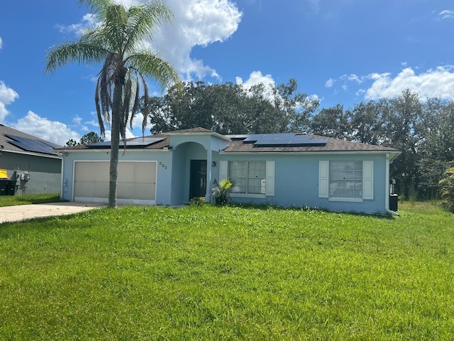 single story home featuring a garage, solar panels, and a front lawn