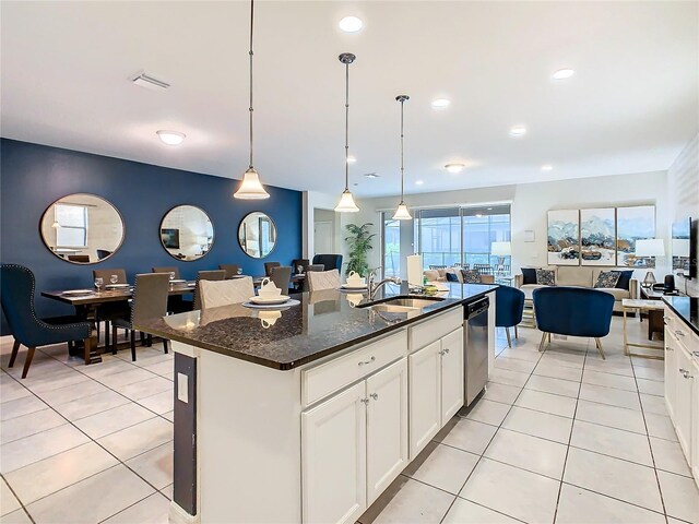 kitchen with white cabinets, decorative light fixtures, sink, and an island with sink