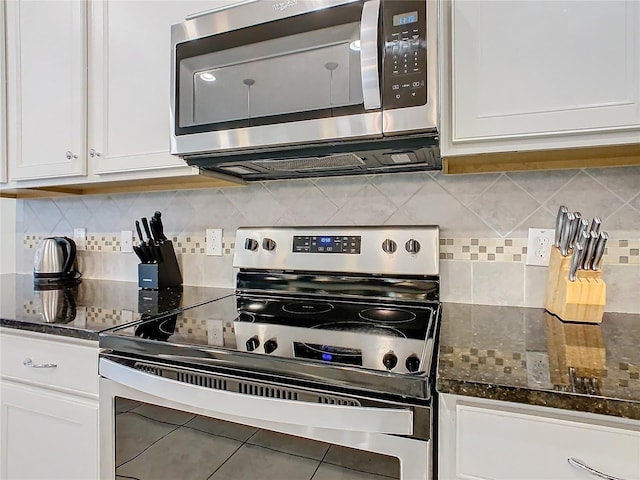 kitchen featuring backsplash, appliances with stainless steel finishes, dark stone counters, and white cabinets