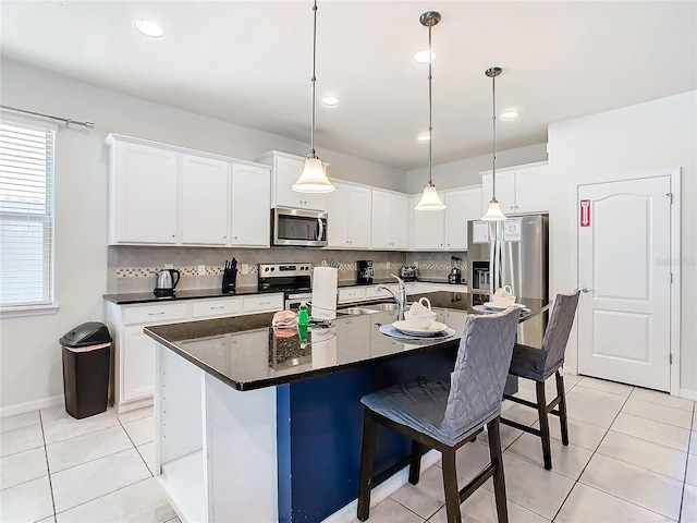 kitchen with a kitchen island with sink, stainless steel appliances, and white cabinets