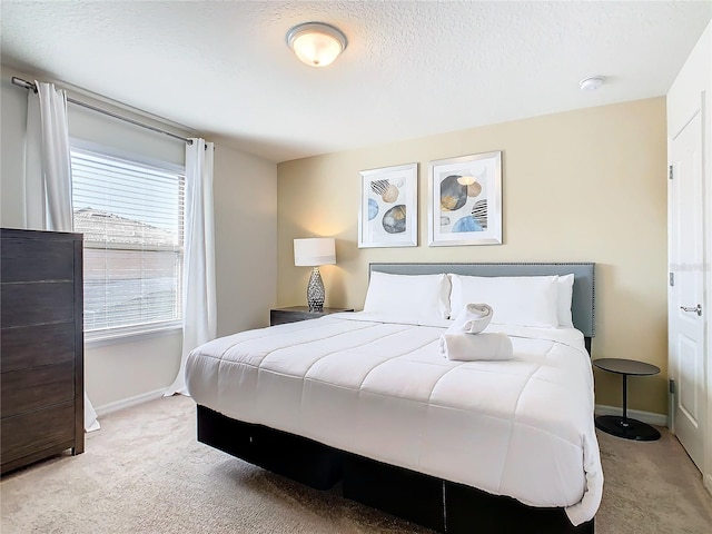 bedroom with a textured ceiling and light colored carpet