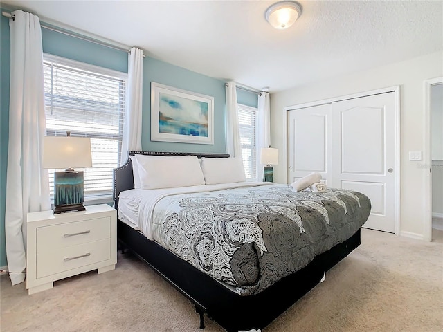 bedroom featuring a closet, multiple windows, and light colored carpet