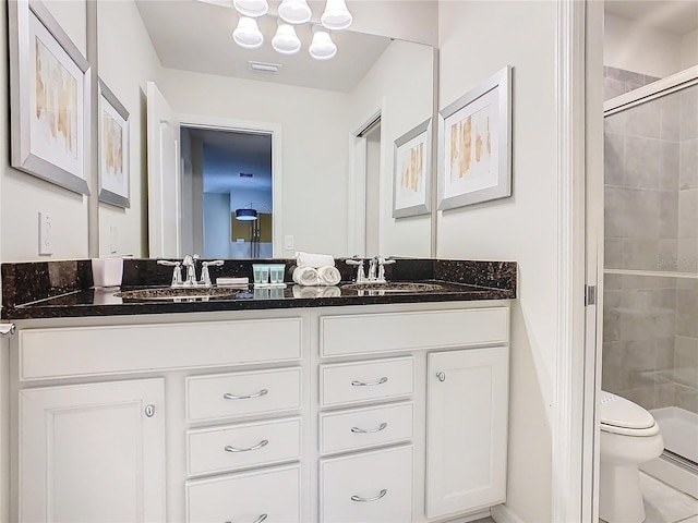 bathroom featuring a shower with door, vanity, and toilet