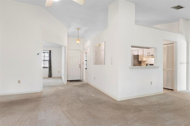 empty room featuring light carpet, vaulted ceiling, and ceiling fan