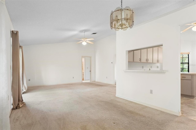 unfurnished living room with high vaulted ceiling, light carpet, and a chandelier