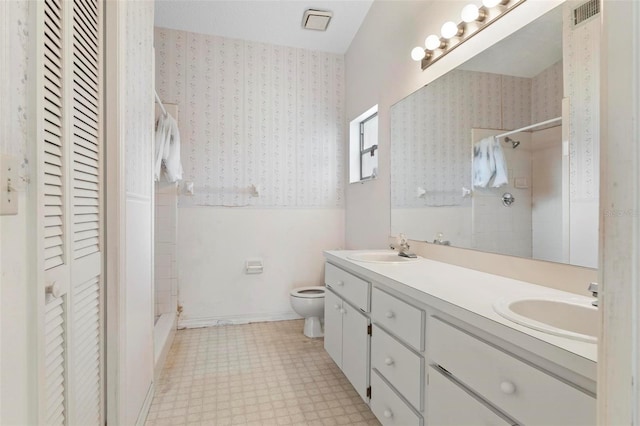 bathroom with a tile shower, vanity, and toilet