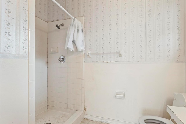 bathroom with vanity, toilet, and a tile shower