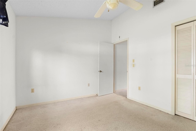 unfurnished bedroom with ceiling fan, light colored carpet, a closet, and high vaulted ceiling