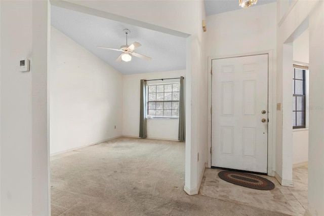 foyer entrance featuring vaulted ceiling, ceiling fan, and light colored carpet