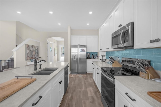 kitchen with white cabinets, light stone counters, sink, and appliances with stainless steel finishes