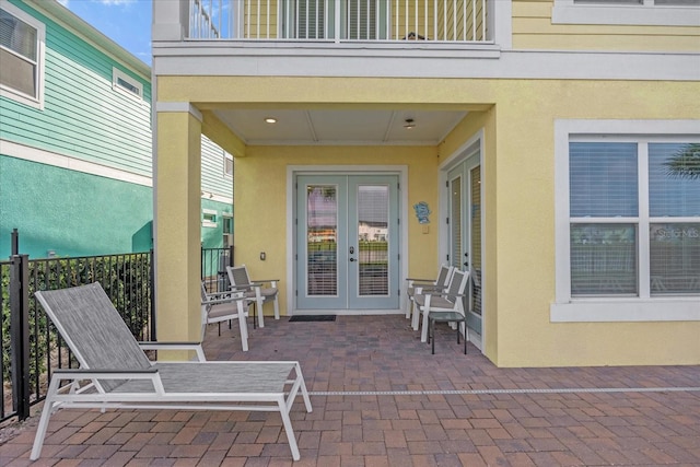 entrance to property featuring a balcony, a patio, and french doors