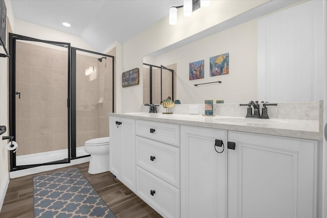 bathroom with vanity, toilet, a shower with door, and vaulted ceiling