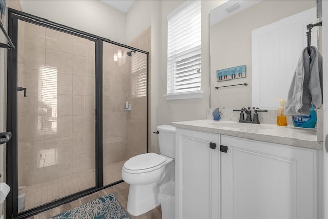 bathroom featuring tile patterned flooring, vanity, an enclosed shower, and toilet