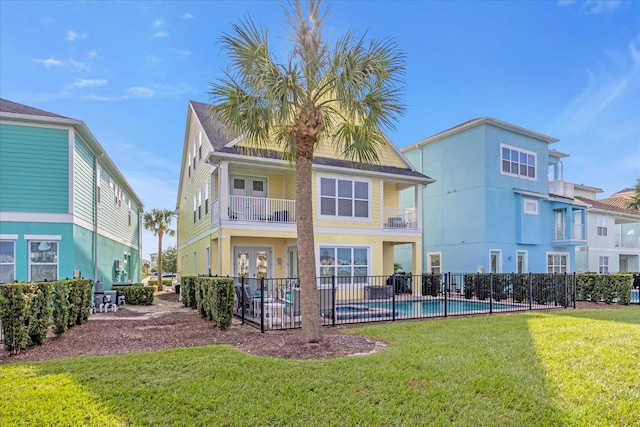 rear view of property featuring a fenced in pool and a lawn