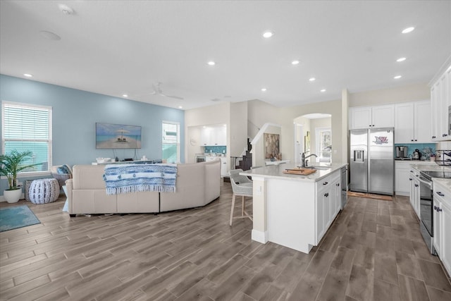 kitchen featuring white cabinets, appliances with stainless steel finishes, a center island with sink, and sink