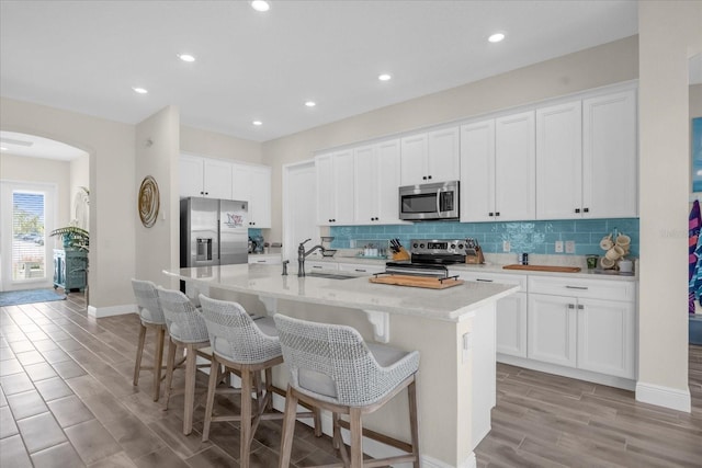 kitchen with a kitchen island with sink, sink, white cabinets, and stainless steel appliances