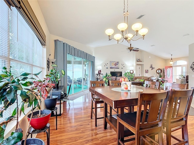 dining room with ceiling fan with notable chandelier, light hardwood / wood-style floors, lofted ceiling, and a wealth of natural light