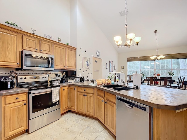 kitchen featuring a chandelier, decorative light fixtures, tile counters, high vaulted ceiling, and appliances with stainless steel finishes