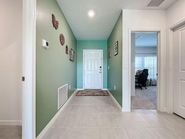 doorway to outside with a textured ceiling and light tile patterned floors