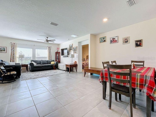 living room featuring light tile patterned flooring, a textured ceiling, and ceiling fan