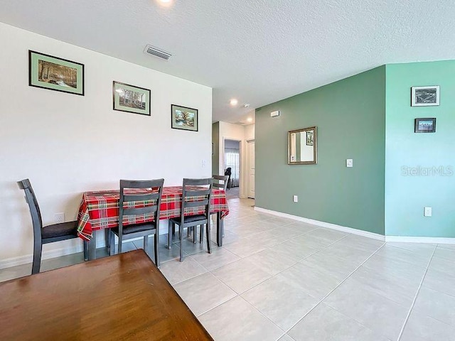 dining space featuring a textured ceiling and light tile patterned floors