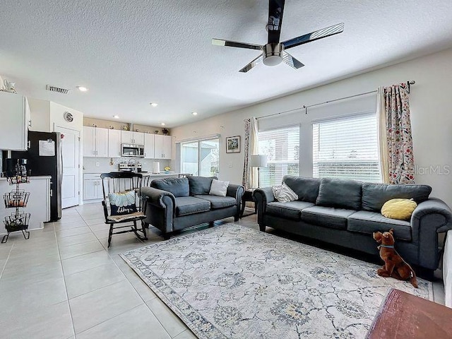 tiled living room with ceiling fan and a textured ceiling