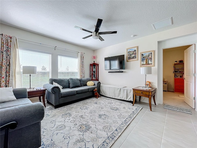 living room featuring ceiling fan, tile patterned floors, and a textured ceiling