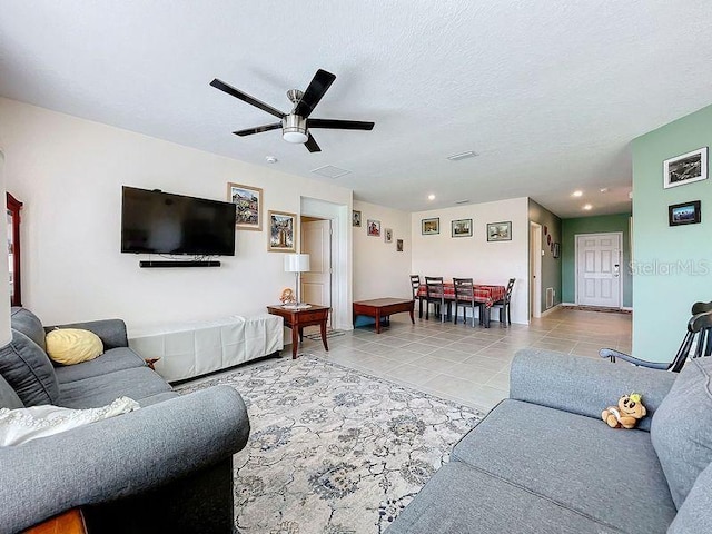 living room with ceiling fan, a textured ceiling, and light tile patterned flooring