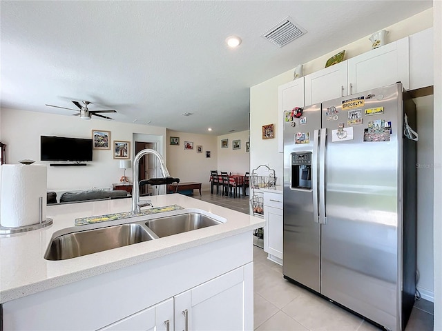 kitchen featuring sink, stainless steel fridge with ice dispenser, light tile patterned floors, white cabinetry, and ceiling fan