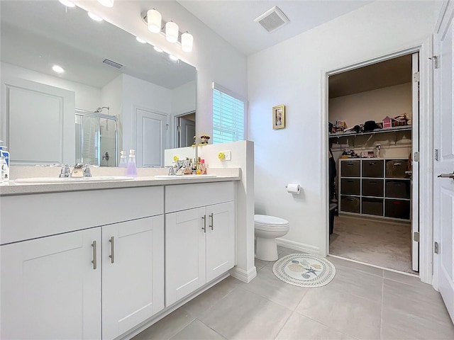 bathroom featuring vanity, a shower with shower door, toilet, and tile patterned floors