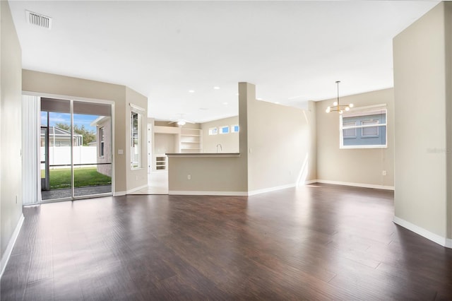 unfurnished living room featuring ceiling fan with notable chandelier, sink, built in features, and dark hardwood / wood-style floors