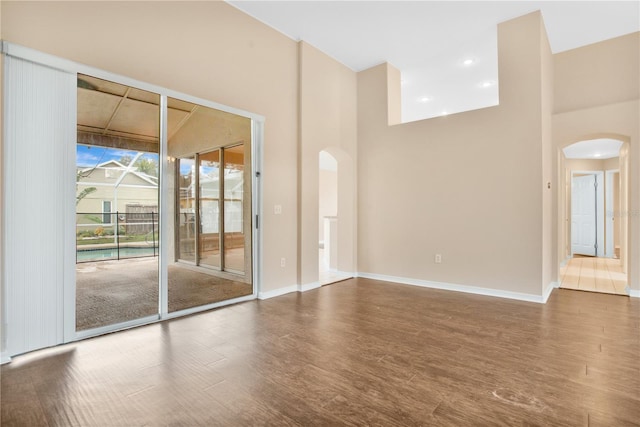 spare room with hardwood / wood-style flooring and a towering ceiling