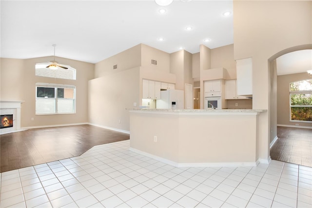 kitchen featuring kitchen peninsula, light wood-type flooring, white cabinets, white appliances, and ceiling fan