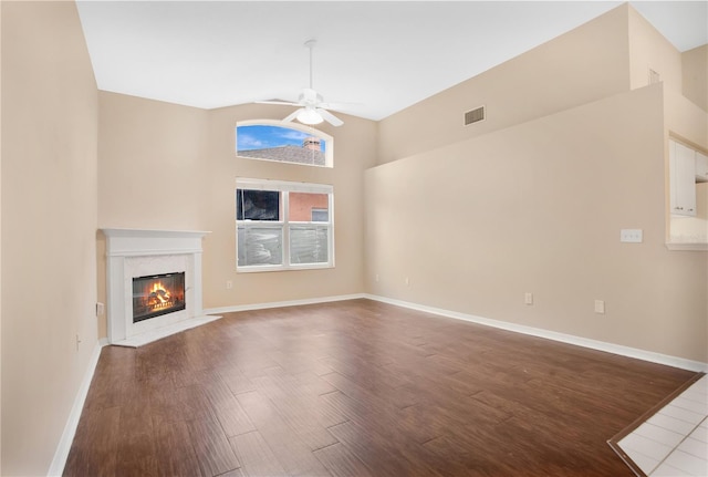 unfurnished living room with ceiling fan, a high ceiling, and dark hardwood / wood-style floors