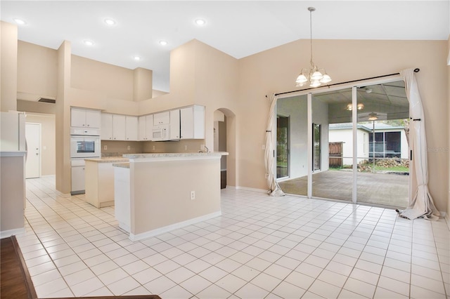 kitchen with high vaulted ceiling, a chandelier, pendant lighting, and white cabinets