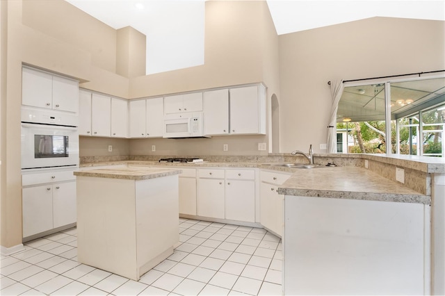 kitchen with a kitchen island, sink, white cabinets, and white appliances