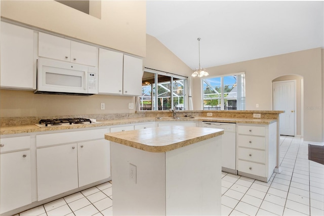 kitchen featuring a kitchen island, vaulted ceiling, pendant lighting, white cabinets, and white appliances